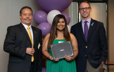 Staff stand with a student holding an award